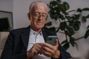 自宅でスマートフォンを操作する富山県のシニア世代の男性のイメージ