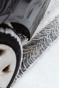雪道に残る車のタイヤ跡と冬用タイヤ|富山の冬に向けたスタッドレスタイヤ交換のイメージ