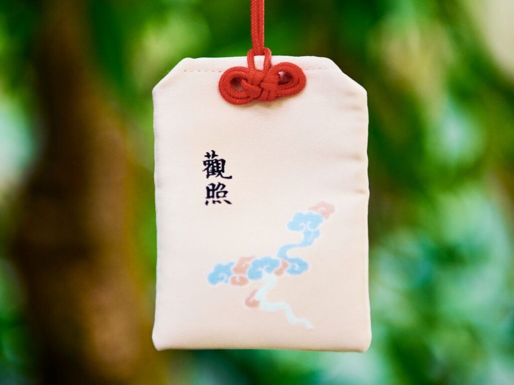 赤いひもで吊るされた白いお守り（富山でのお守り・お札の処分・返納のイメージ）